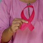 person holding pink ribbon for breast cancer awareness month