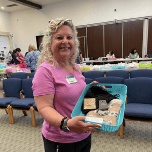 Chemocessories Founder, Iris Lee Knell, wearing pink and holding a basket containing the 20,000th Chemocessories set