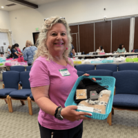Chemocessories Founder, Iris Lee Knell, wearing pink and holding a basket containing the 20,000th Chemocessories set